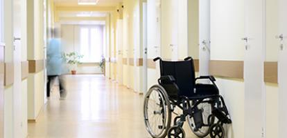 Wheelchair in a long, hospital hallway.