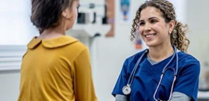 Nurse holds young patient's hand and smiles in a doctor's office