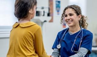 Nurse holds young patient's hand and smiles in a doctor's office