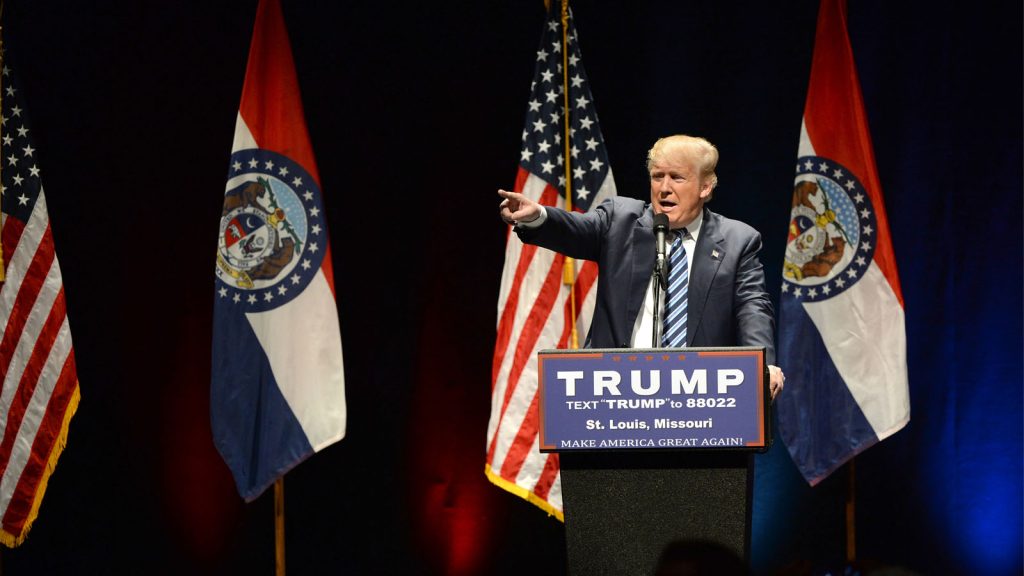 Donald Trump pointing while he makes a speech from a podium.