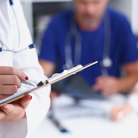 Female doctor hold clipboard pad and fill medical history list with silver pen. Physical illness prevention 911 prescribe remedy ward round therapeutist assistance healthy lifestyle concept