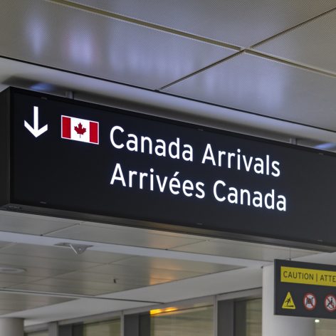 Airport sign indicating Canada Arrivals in English and French with an image of the Canadian Flag